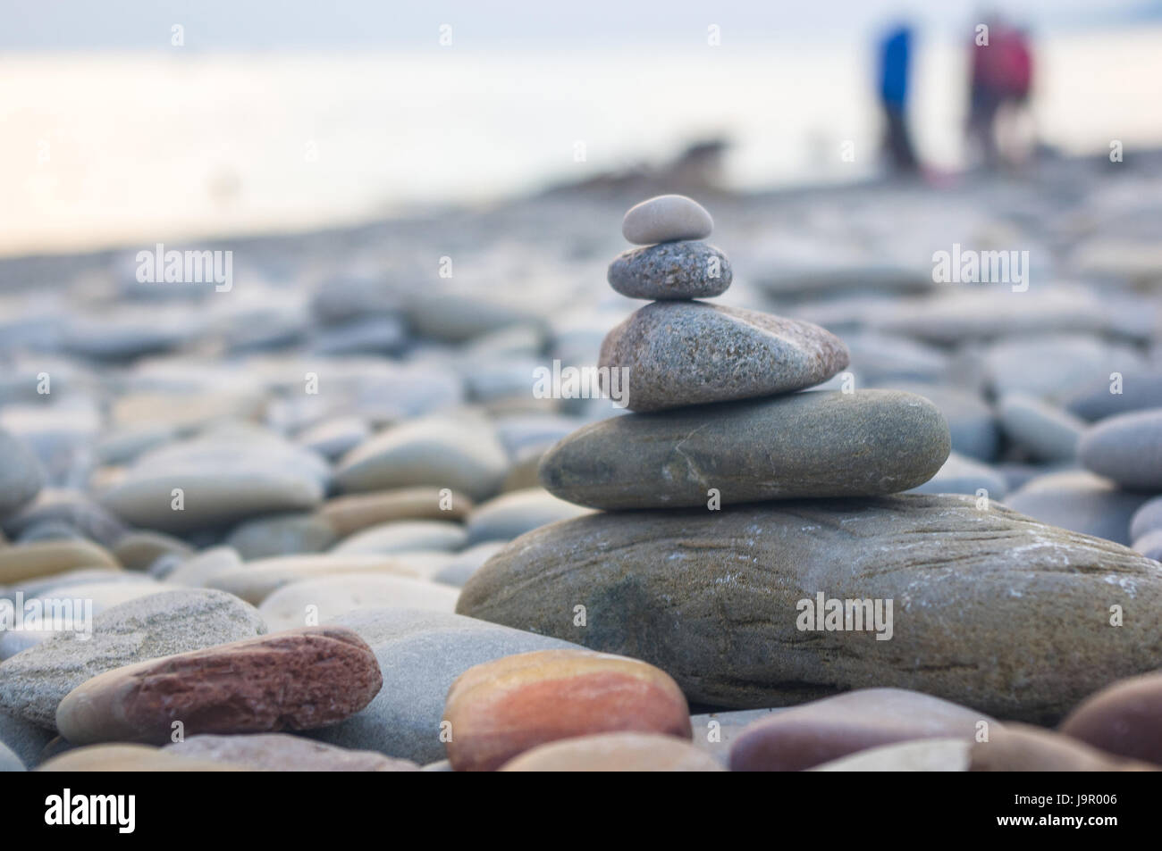 Piramide piegata Zen pietre ghiaia sul mare spiaggia al tramonto Foto Stock