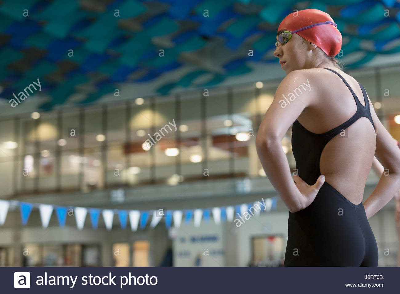 Giovane donna nuotatore pronto, in piedi con le mani sui fianchi Foto Stock
