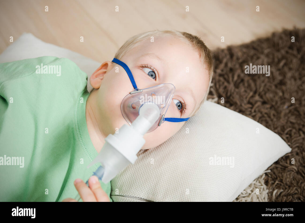 Ragazzo che inalazione con nebulizzatore a casa. bambino asma inalatore nebulizzatore di inalazione di vapore tosse malati concept Foto Stock