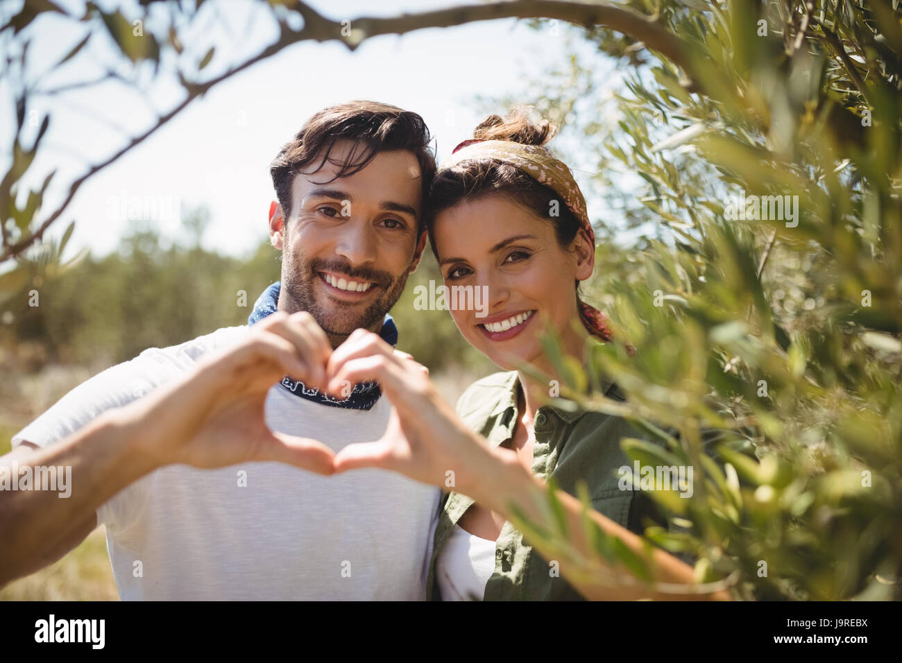 Ritratto di Coppia sorridente messa a forma di cuore da alberi di olivo agriturismo Foto Stock