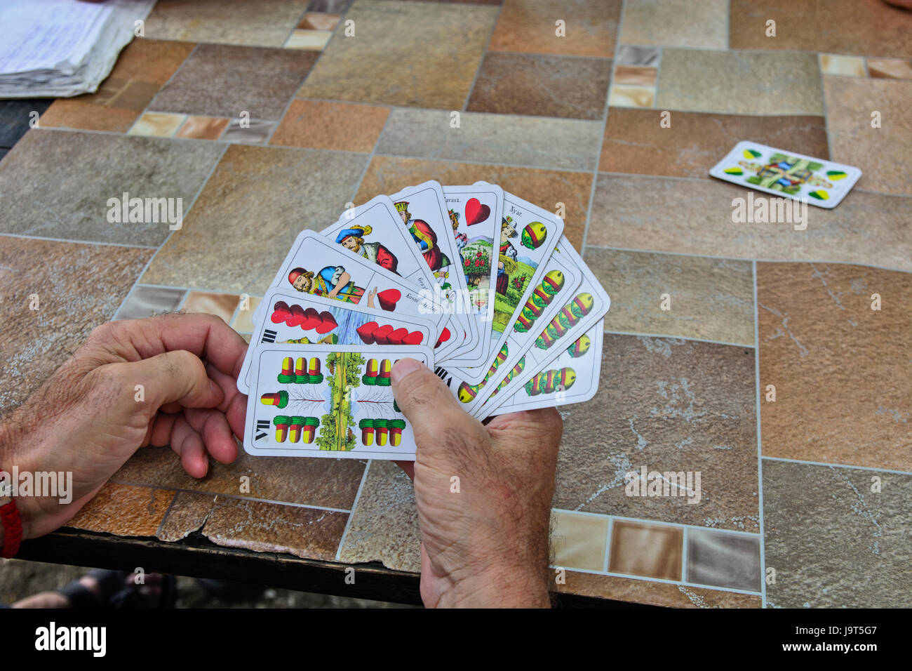 Vecchio gentleman giocando a carte ad un tavolo condiviso nel parco. Foto Stock