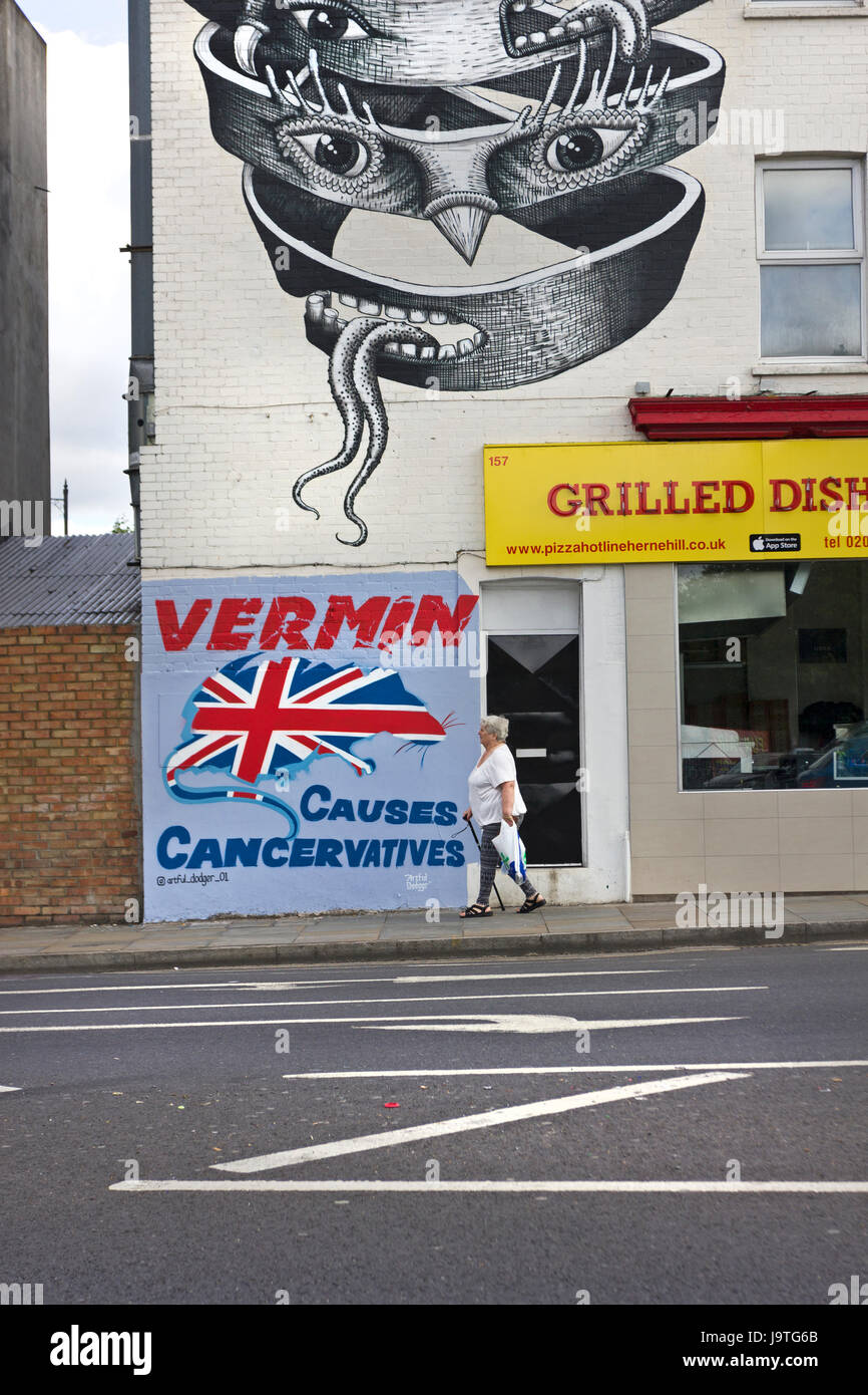 Per 'VERMIN provoca Cancervatives' nuovo murale politico da artista di strada evasore Artful su una parete in Herne Hill, SE London. Al di sopra di esso di un fantastico murale ispirato da M. C. Escher da londinese muralista e artista di strada, flemma. Foto Stock