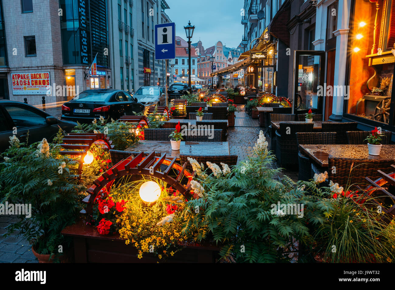 Riga, Lettonia - 3 Luglio 2016: tavoli liberi di una Street Cafe con illuminazione decorativa in serata o illuminazione notturna nella città vecchia di Kungu Street Foto Stock