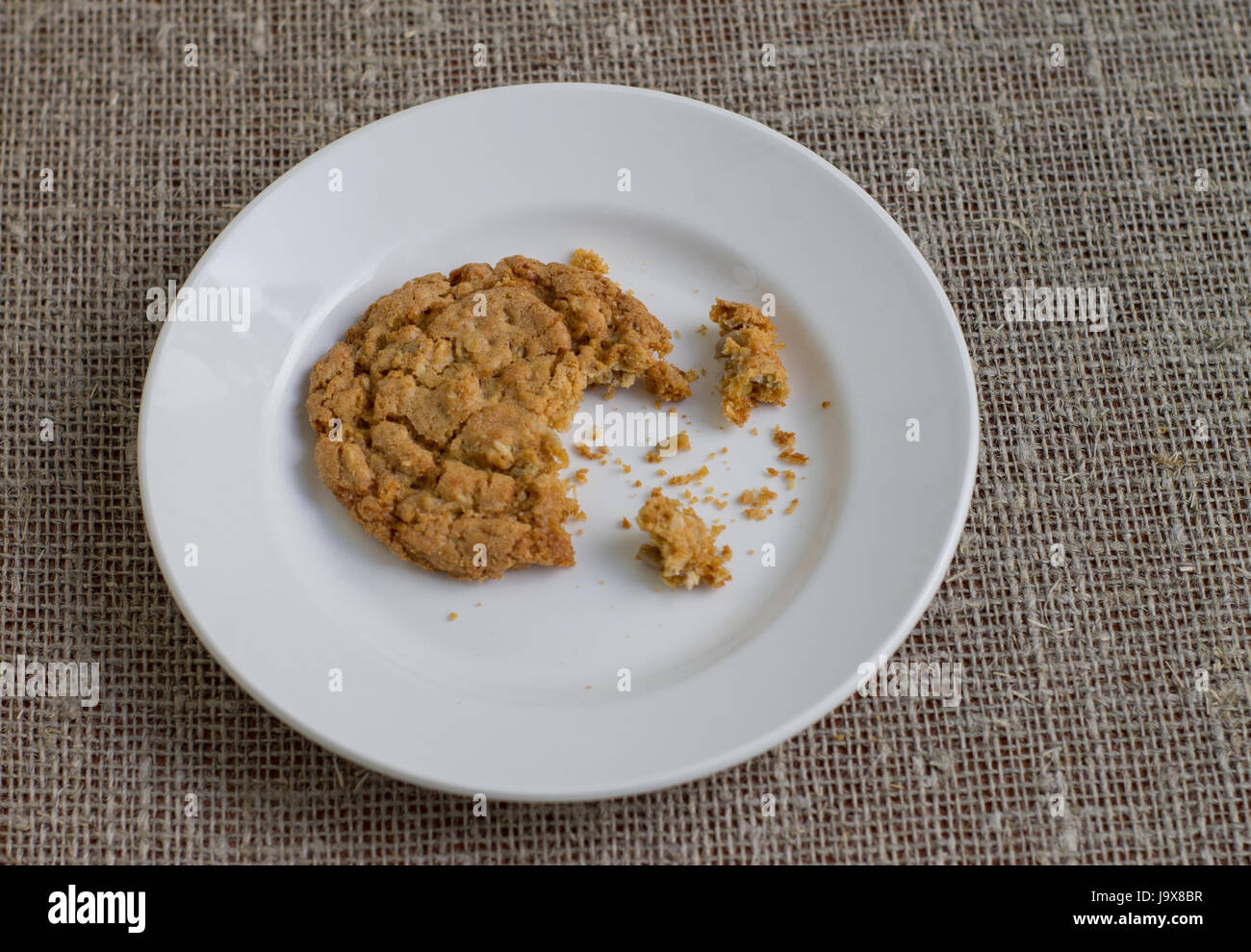 Un morso cookie su una piastra bianca. Tela di sfondo. Foto Stock