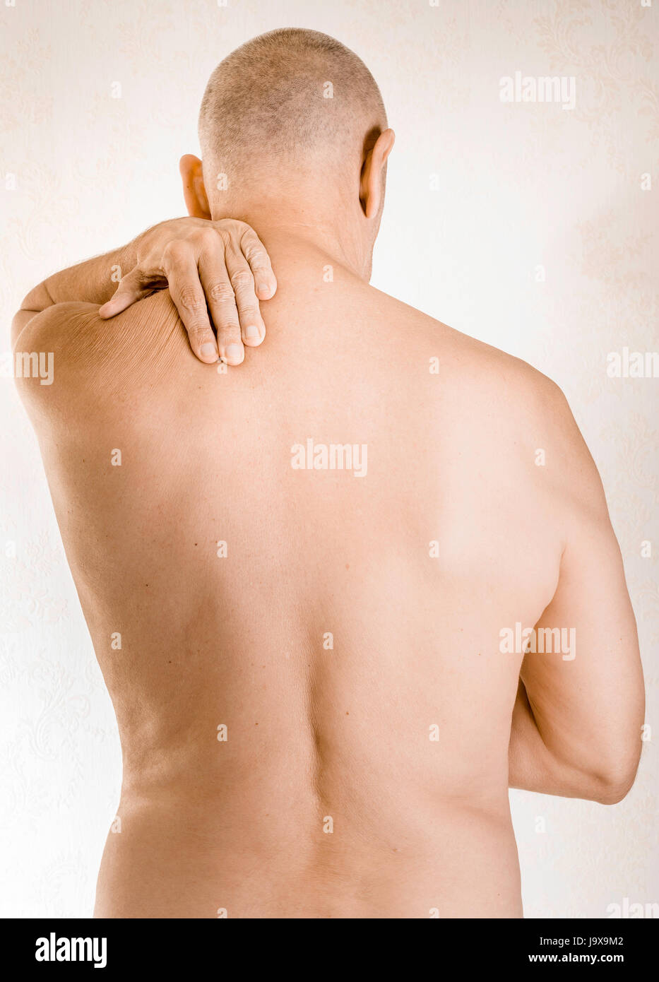L'uomo massaggiare la sua spalla, a causa di un muscolo trapezius dolore a causa di uno spostamento di una vertebra dorsale sfregamento su un nervo Foto Stock