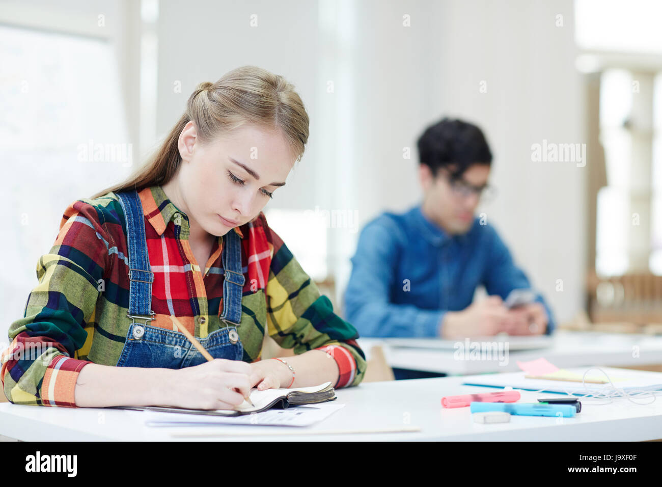 Un diligente studente iscritto lecture da scrivania in college Foto Stock