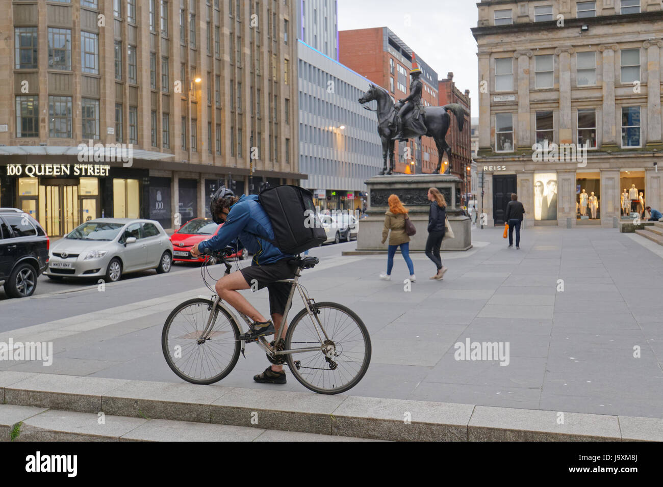 Deliveroo Uber bikers consegna i driver per i ciclisti su strada per somministrare a Glasgow in vista della testa conica Duca di Wellington statua Foto Stock