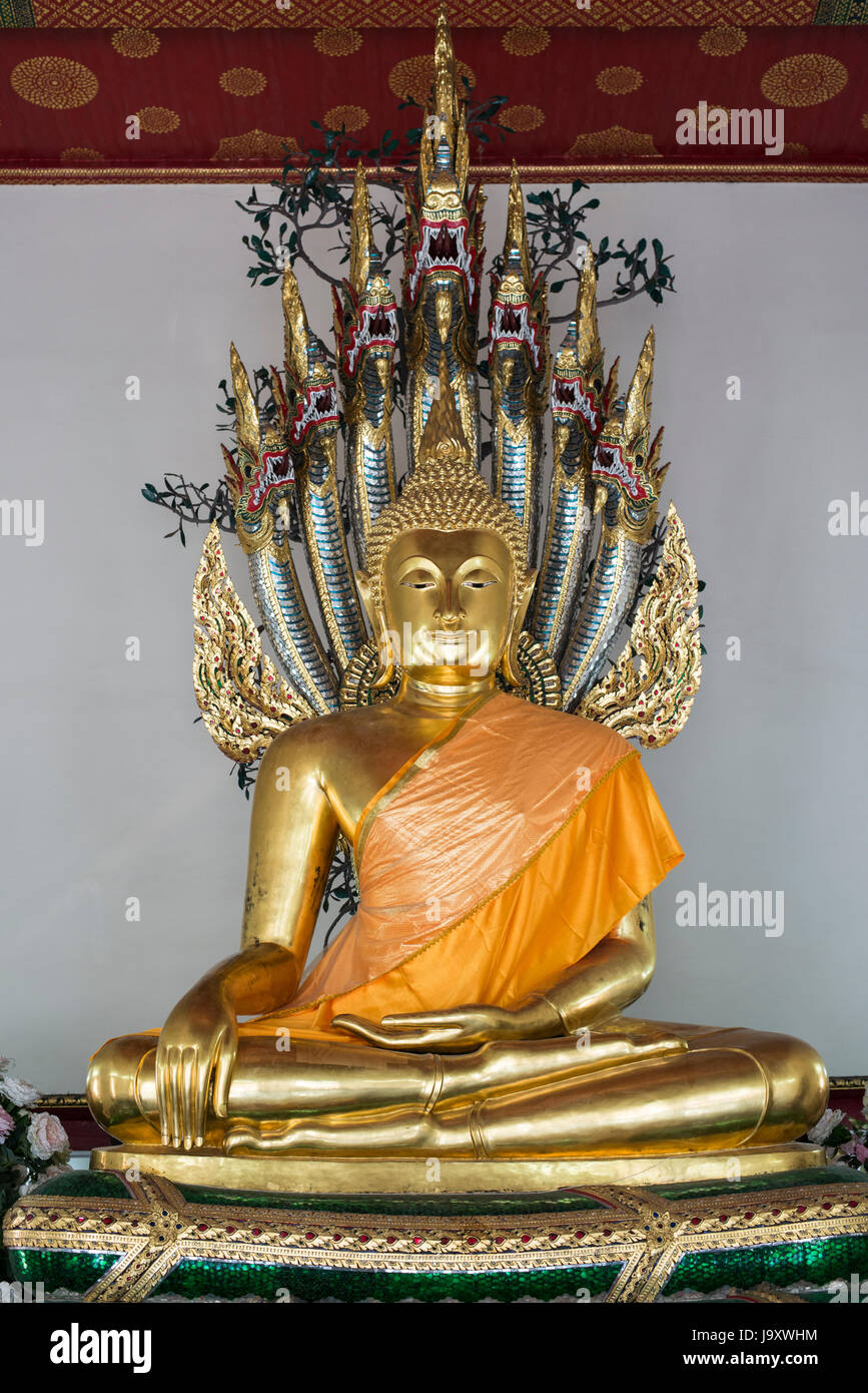 Un colore oro statua del Buddha si siede in un santuario a Wat Pho, Bangkok, Thailandia Foto Stock