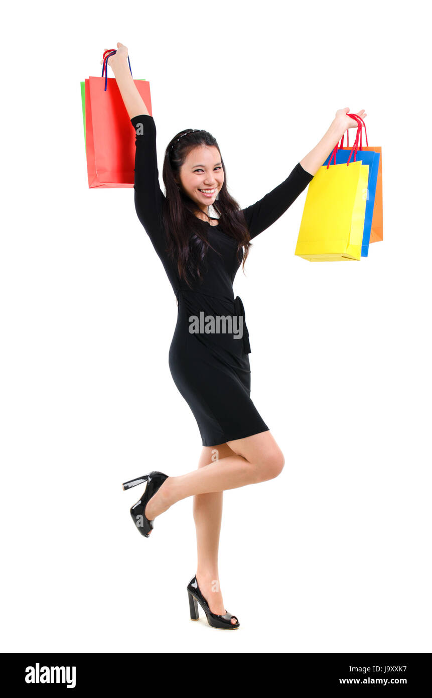 Eccitato shopping asiatiche donna sorridenti tenendo molte borse per lo shopping. Asian shopper ragazza isolato su sfondo bianco in piena lunghezza. Bellissima gara di misto del Caucaso del Sud Est Asiatico modello di donna. Foto Stock