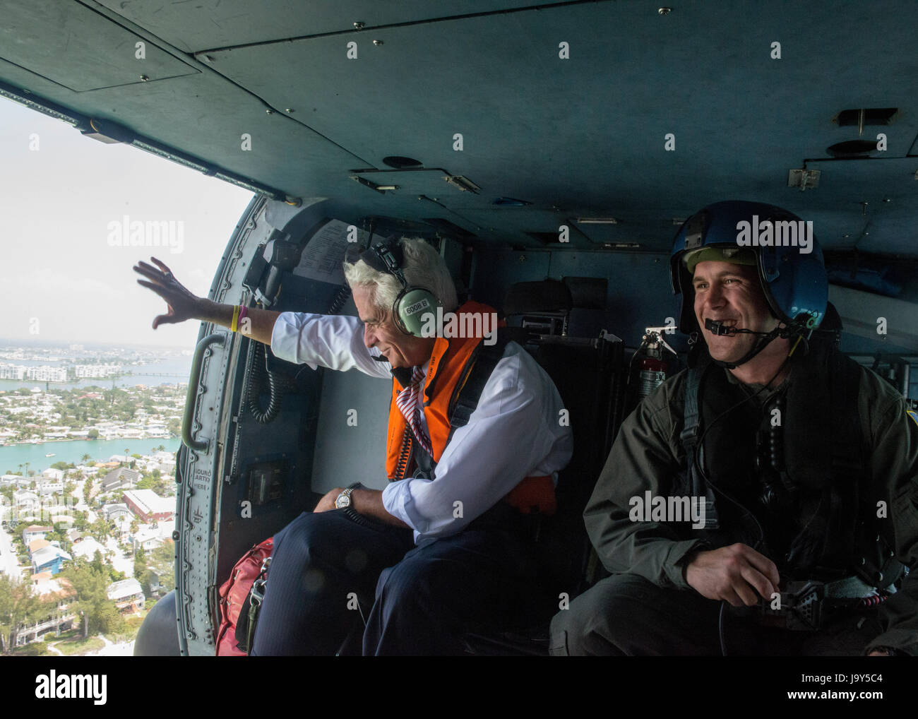 Stati Uniti Florida Congressman Charlie Crist (sinistra) delle forme d'onda al di fuori di un'U.S. Coast Guard elicottero in volo durante una valutazione antenna di erosione lungo la costa della Florida Maggio 30, 2017 in Clearwater, Florida. (Foto di Michael De Nyse /US Coast Guard via Planetpix) Foto Stock