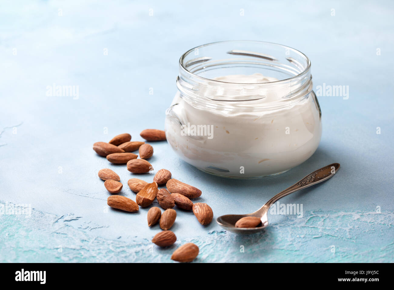 Mandorla yogurt in un vasetto di vetro su un blu sullo sfondo di calcestruzzo Foto Stock
