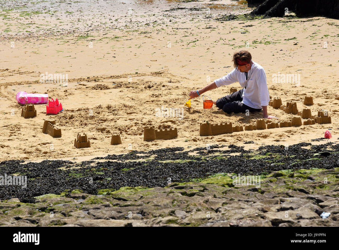 Castelli di sabbia creati da un uomo a Southend sulla spiaggia di Sea. Più castelli che cercano di costruire verso un castello più grande Foto Stock