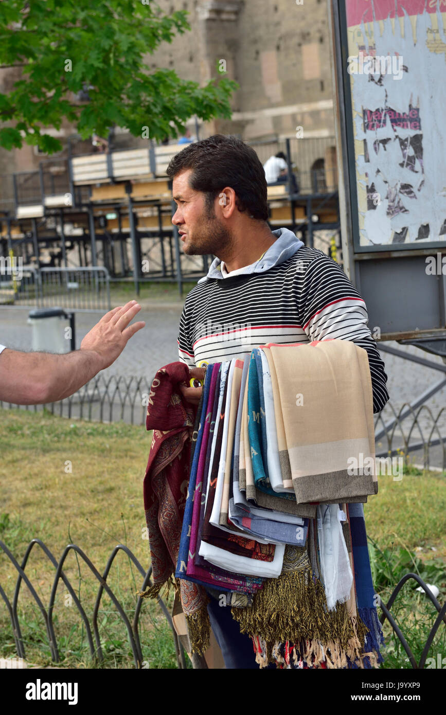 Venditore di strada cercando di vendere sciarpe a Roma essendo cucinare off dal turista maschio Foto Stock