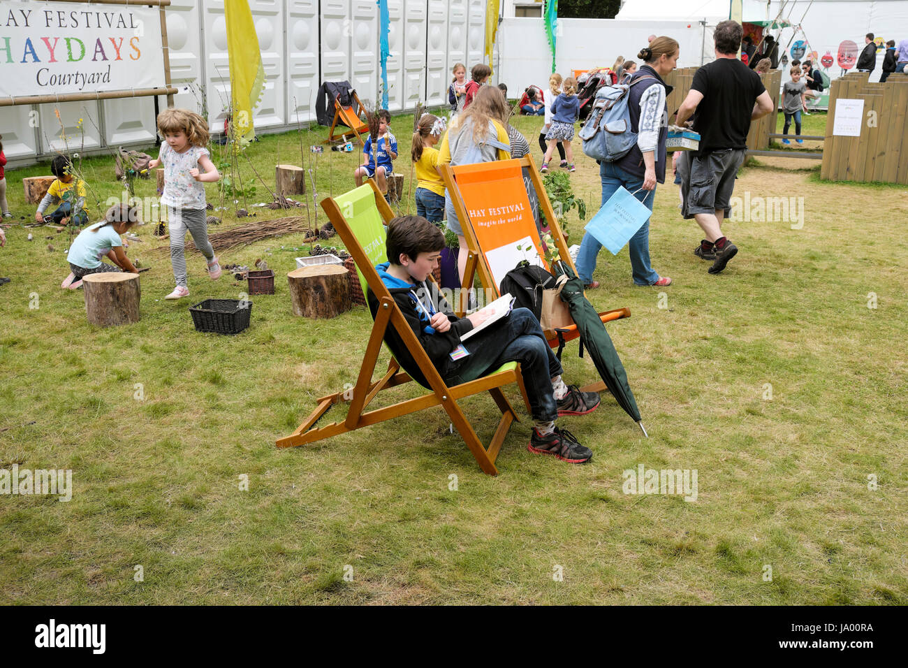 Un ragazzo 12 seduto in una sedia a sdraio a leggere un libro al Festival di fieno, Hay-on-Wye, Wales UK KATHY DEWITT Foto Stock