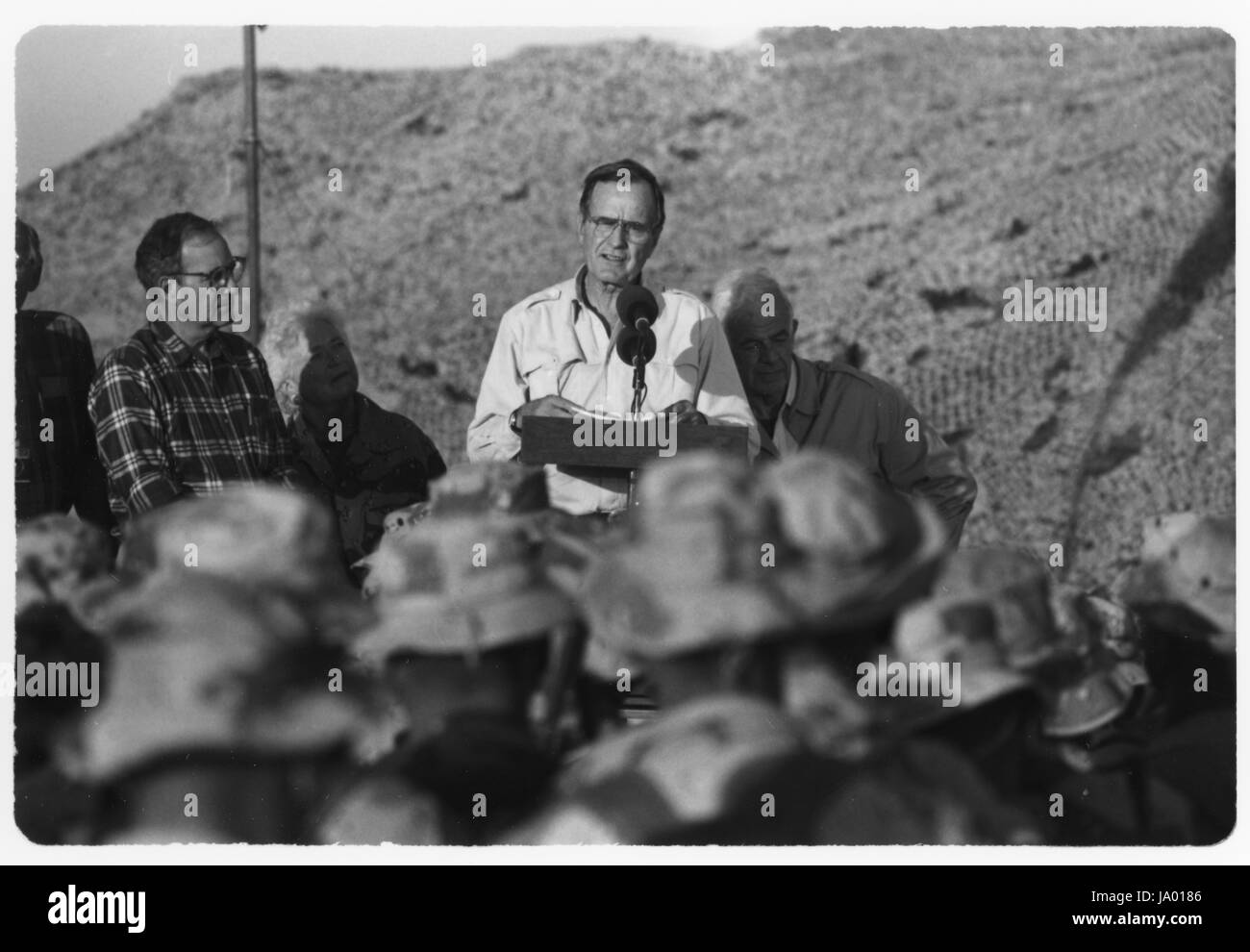 Il presidente George Bush, con casa leader della minoranza Robert H. Michel (sinistra), First Lady Barbara Bush e altoparlante della casa Tom Foley (a destra), parla con i marines presso la prima divisione Marine le operazioni di combattimento centro sul giorno del Ringraziamento durante operazione DESERT SHIELD, Arabia Saudita, 11/23/1990. Foto Stock