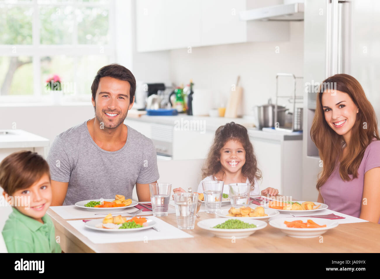Sorridente famiglia avente la cena in cucina Foto Stock