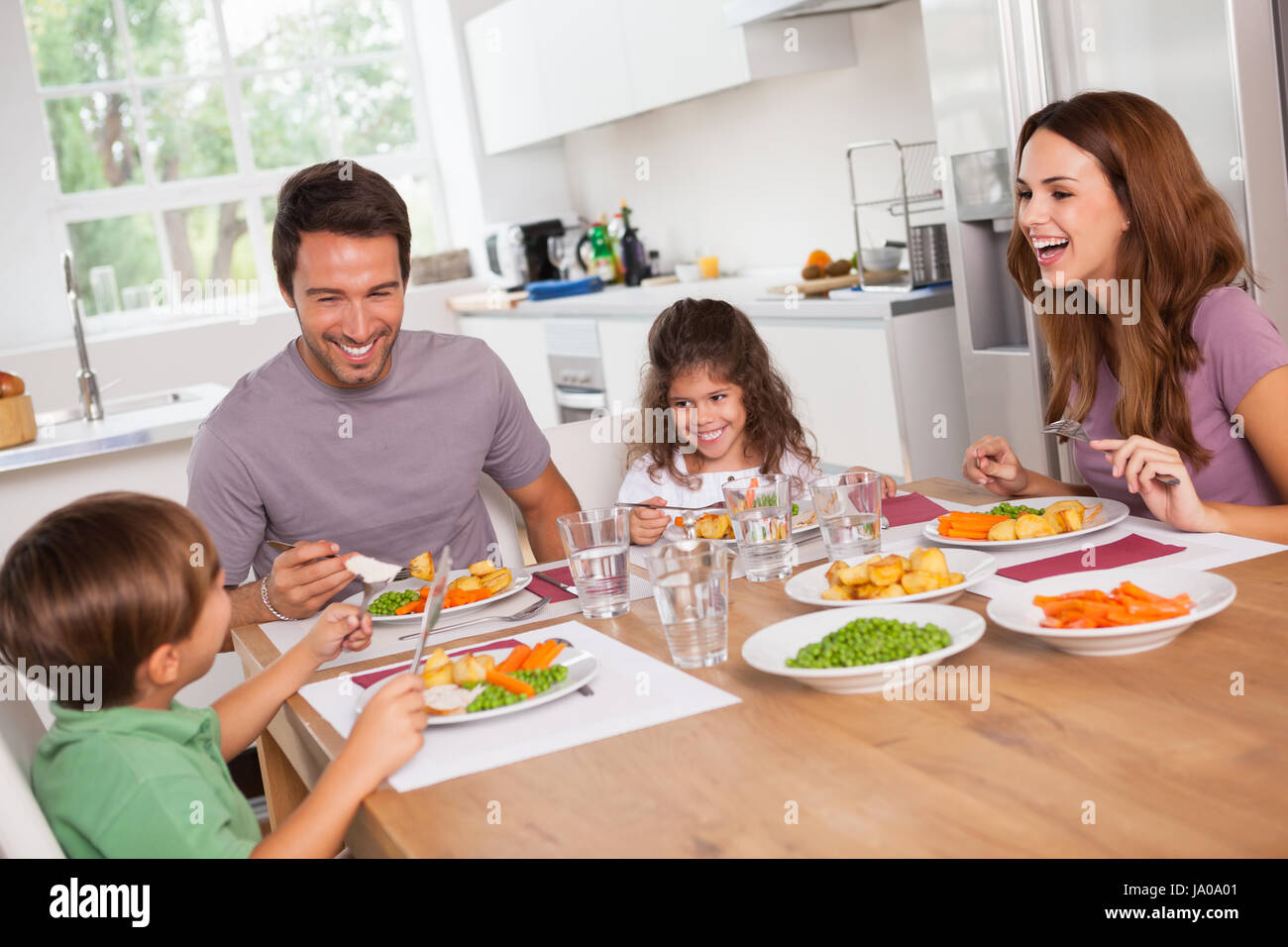 Famiglia di ridere intorno a un buon pasto in cucina Foto Stock