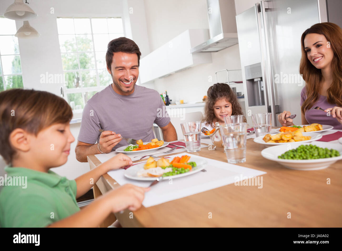 Famiglia sorridente intorno a un buon pasto in cucina Foto Stock
