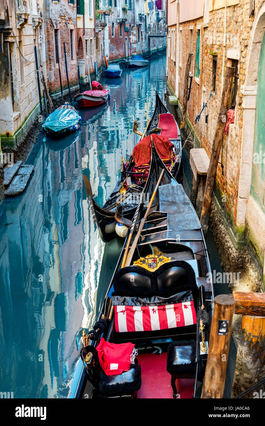 A Venezia, Italia e colorati di scena di due gondole ancorate lungo un canale con vividi riflessi di architettura in acqua e barche a motore. Foto Stock