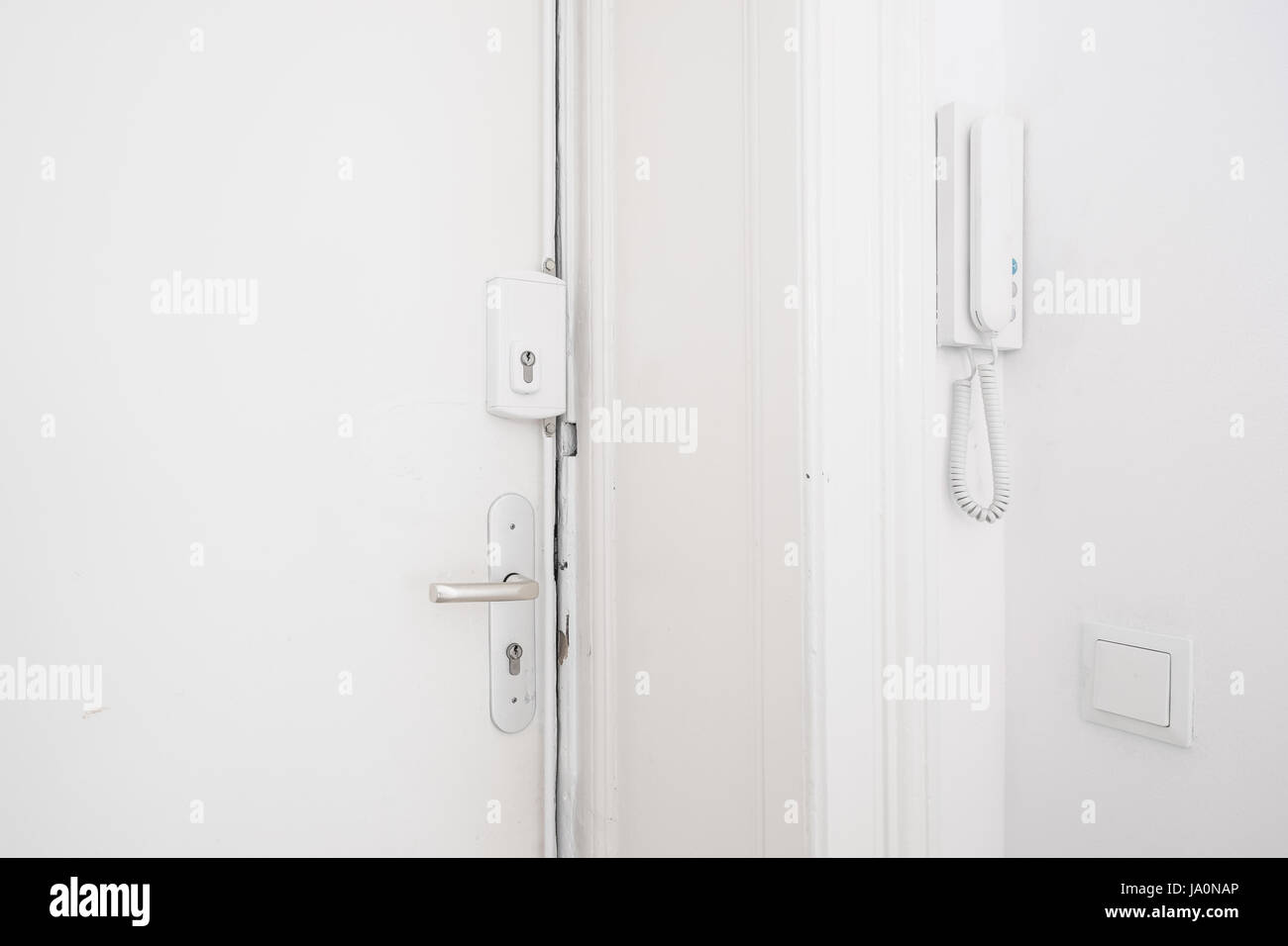 Porta di ingresso maniglia , il blocco della barra di sicurezza e sistema di interfono su bianco appartamento Foto Stock