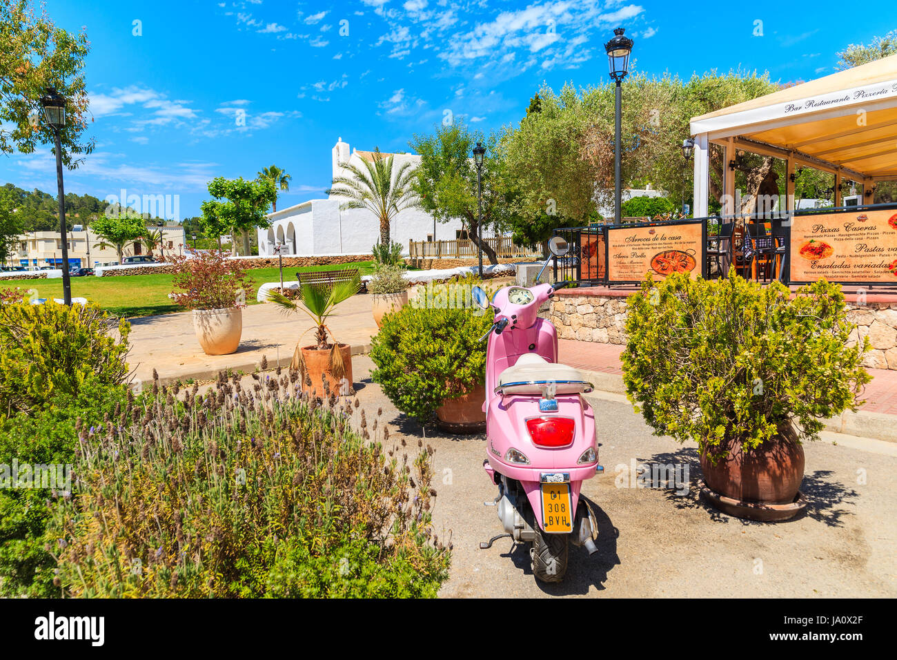 Isola di Ibiza, Spagna - 18 Maggio 2017: classic rosa Vespa scooter parcheggio nel giardino del ristorante tradizionale in Sant Carles de Peralta village, Ibiza è Foto Stock
