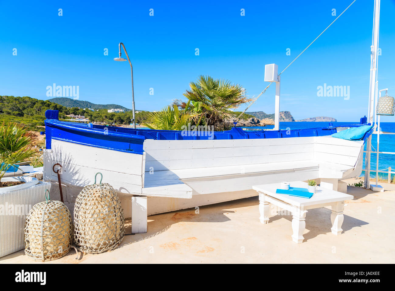 Cranio bianco di una barca da pesca sulla soleggiata terrazza ristorante sulla spiaggia di Cala Nova, isola di Ibiza, Spagna. Foto Stock