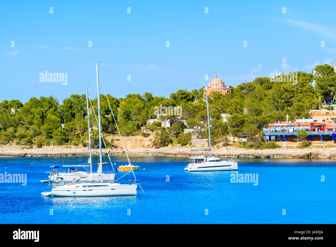 Catamarano barche sul mare blu acqua in Cala Portinatx bay, isola di Ibiza, Spagna Foto Stock