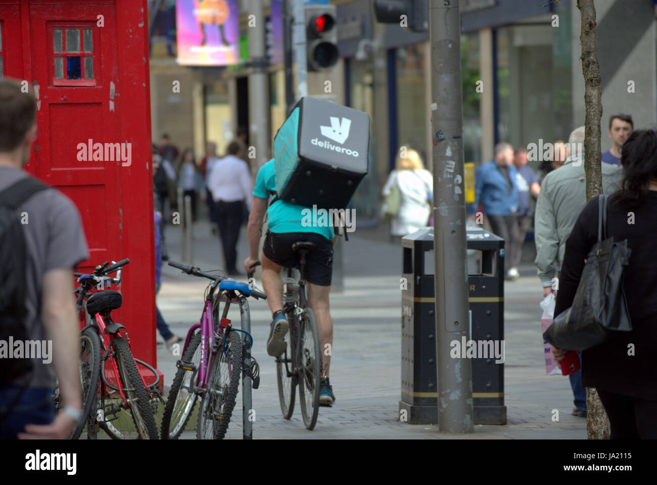 Deliveroo Uber bikers consegna i driver per i ciclisti su strada per somministrare a Glasgow Foto Stock