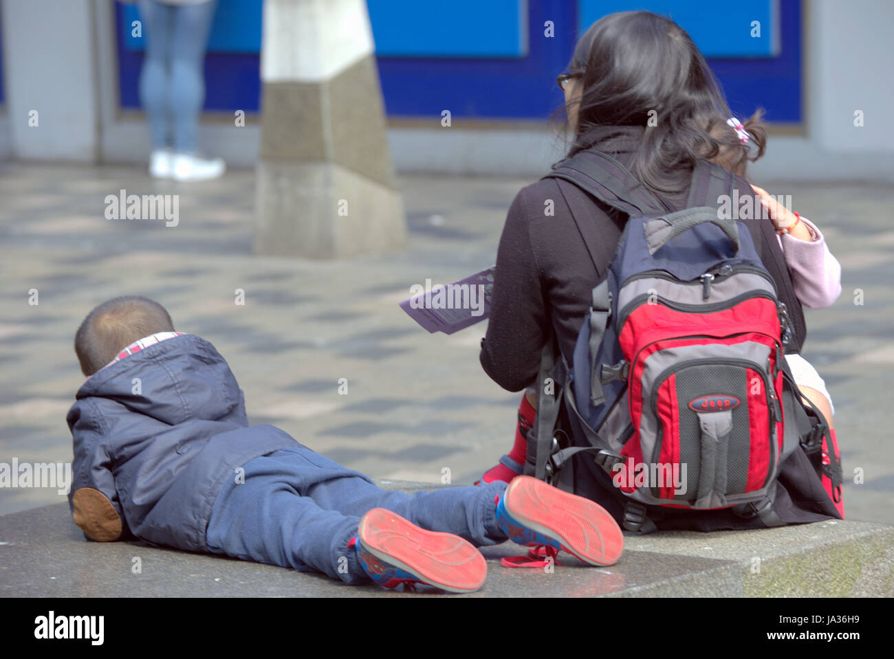 I turisti per le strade di Glasgow Scozia famiglia cinese seduta sul banco di strada Foto Stock