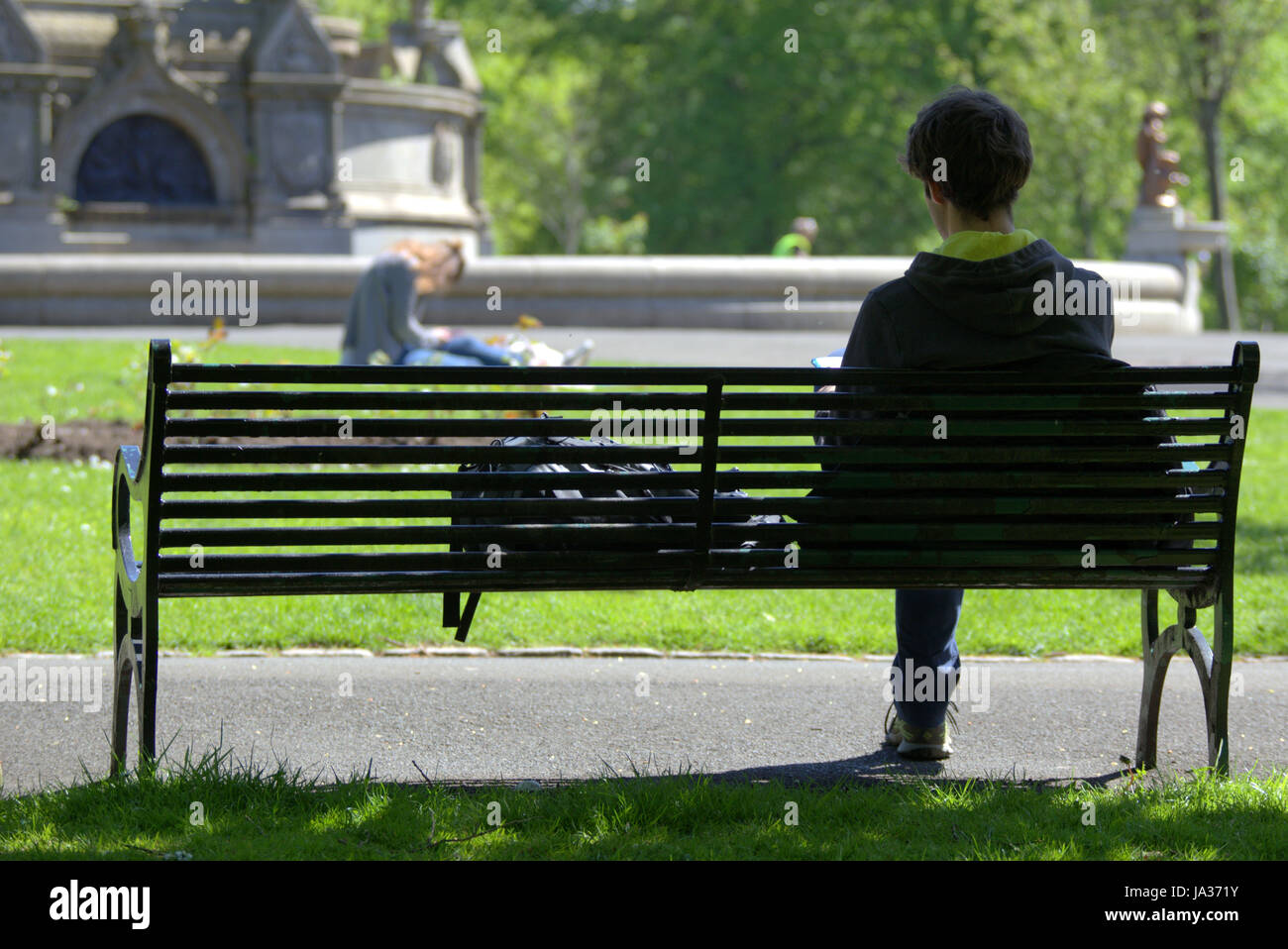 Glasgow Kelvingrove Park scene ragazzo seduto al banco ragazza occhiatura Foto Stock