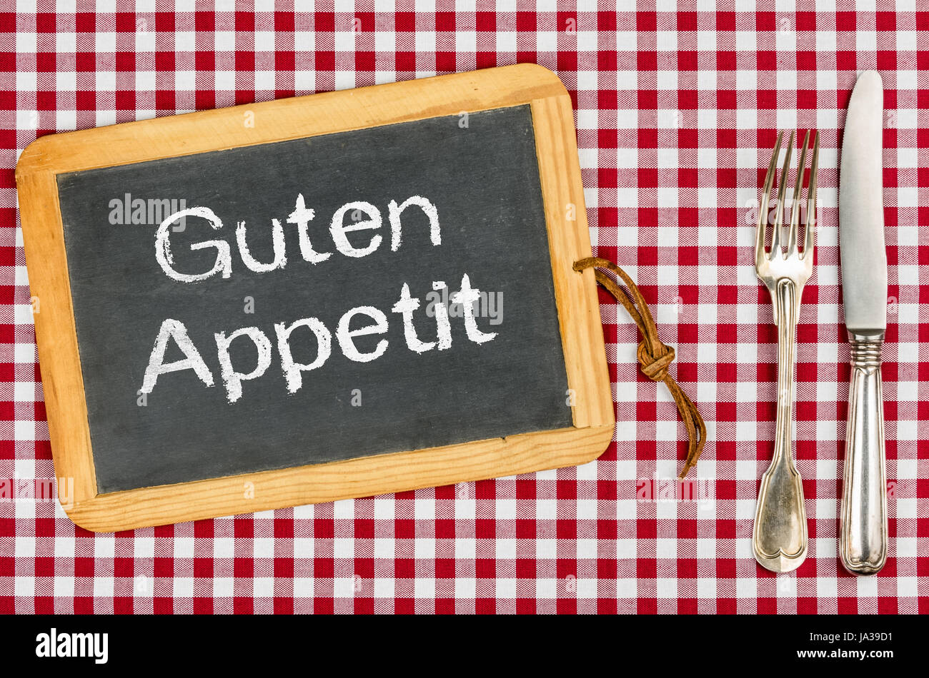 Lavagna con il testo bon appetit su una tovaglia a scacchi Foto Stock