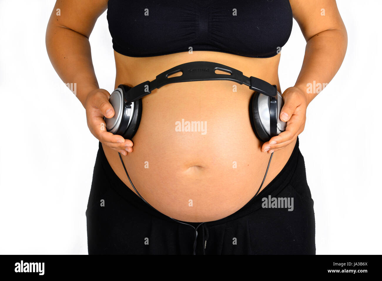 Una vista frontale di una gravidanza bump massiccia indossa le cuffie per  ascoltare il bambino alcune melodie funky Foto stock - Alamy