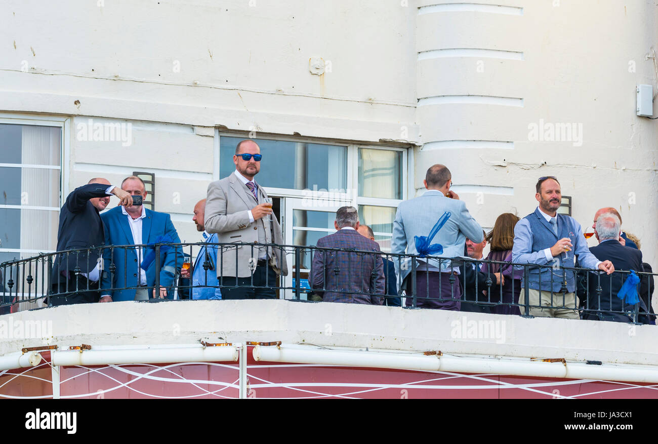 Un gruppo di uomini di mezza età in piedi al di fuori su di un balcone con bevande. Foto Stock