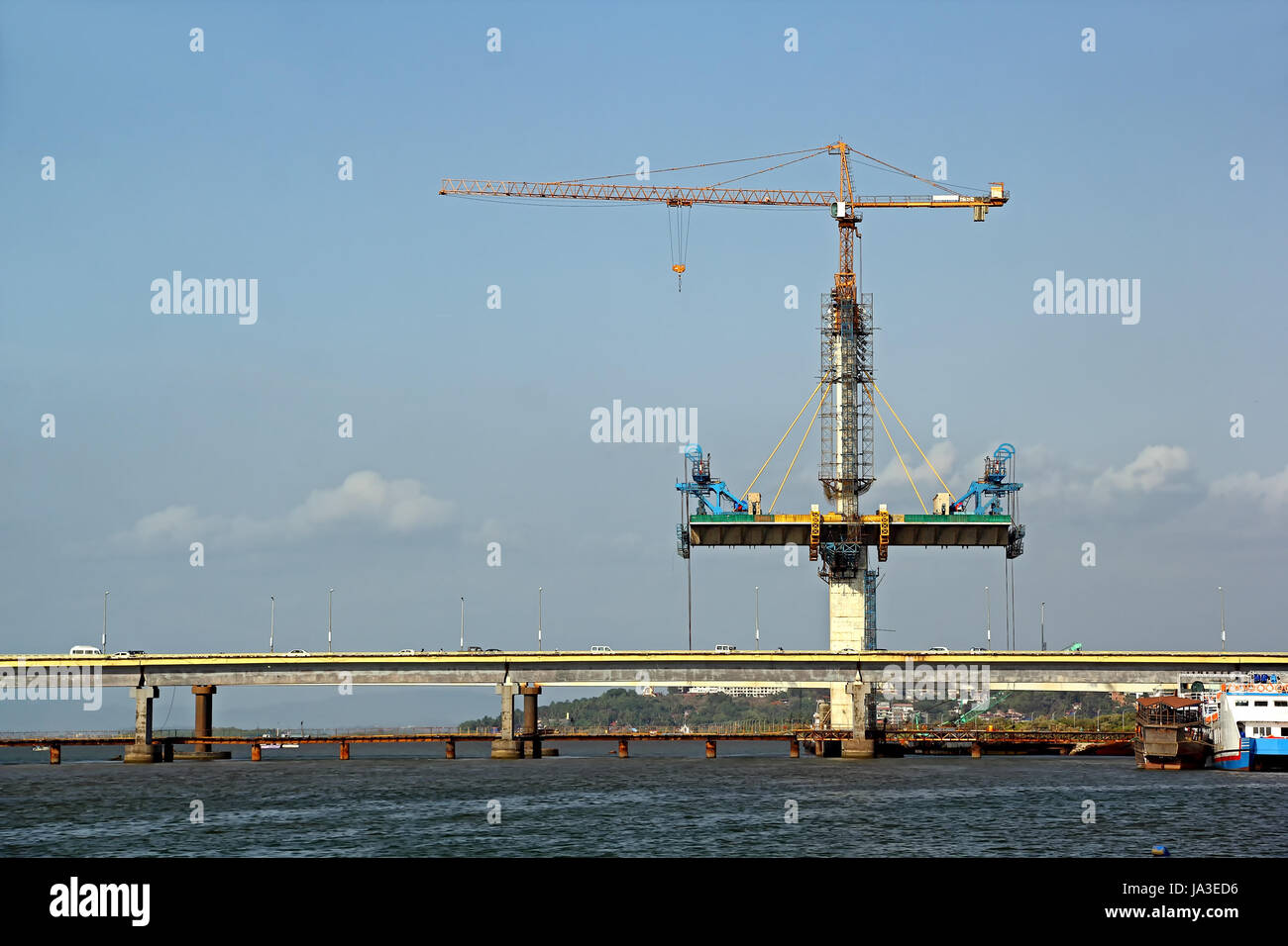 Fasi della costruzione del ponte di ponte strallato su entrambi i lati di un alto molo di cemento mediante gru a torre, costruito sul Fiume Mandovi, Goa. Foto Stock