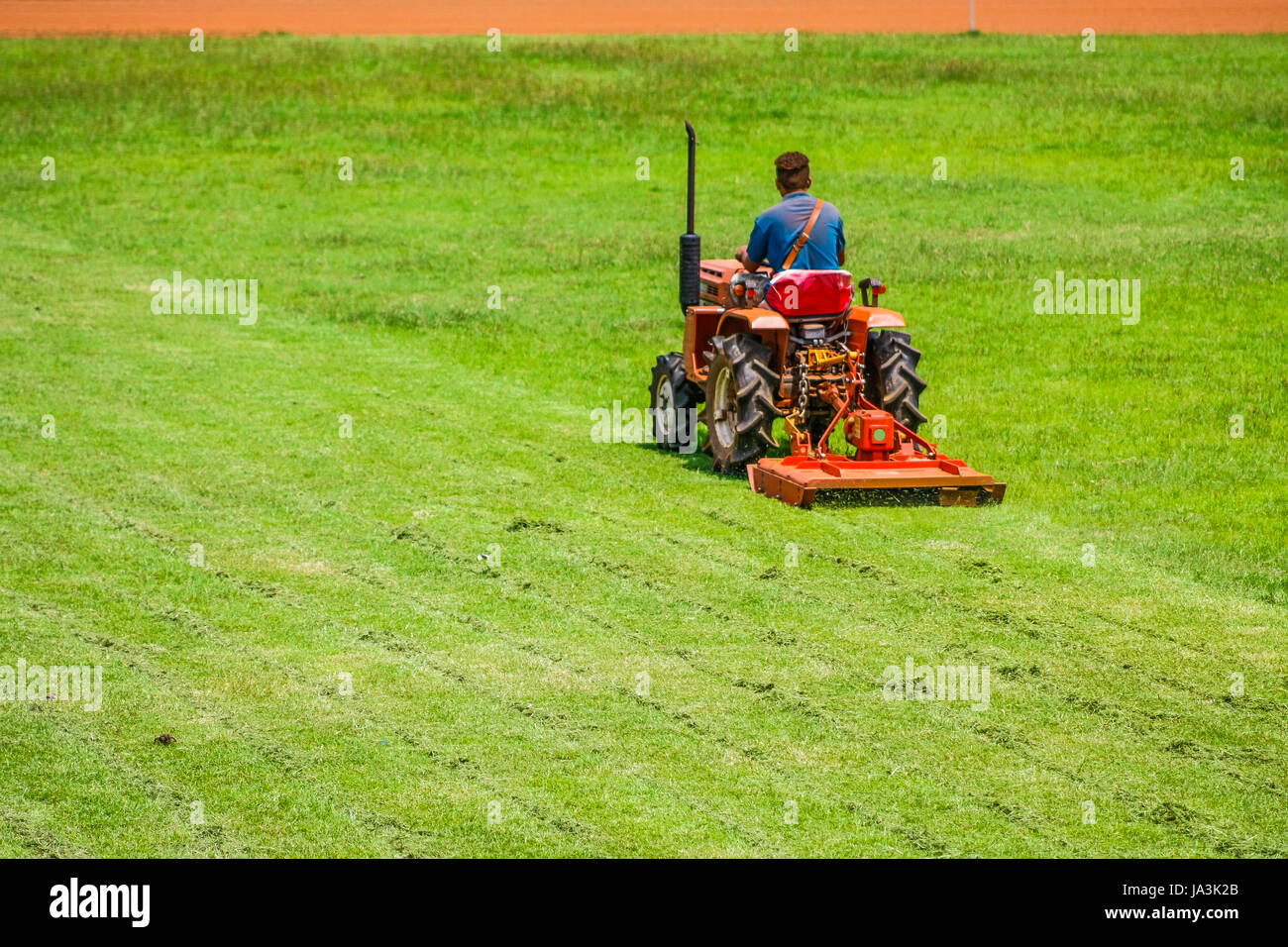 Un uomo sul tosaerba per taglio erba nel campo di calcio Foto stock - Alamy