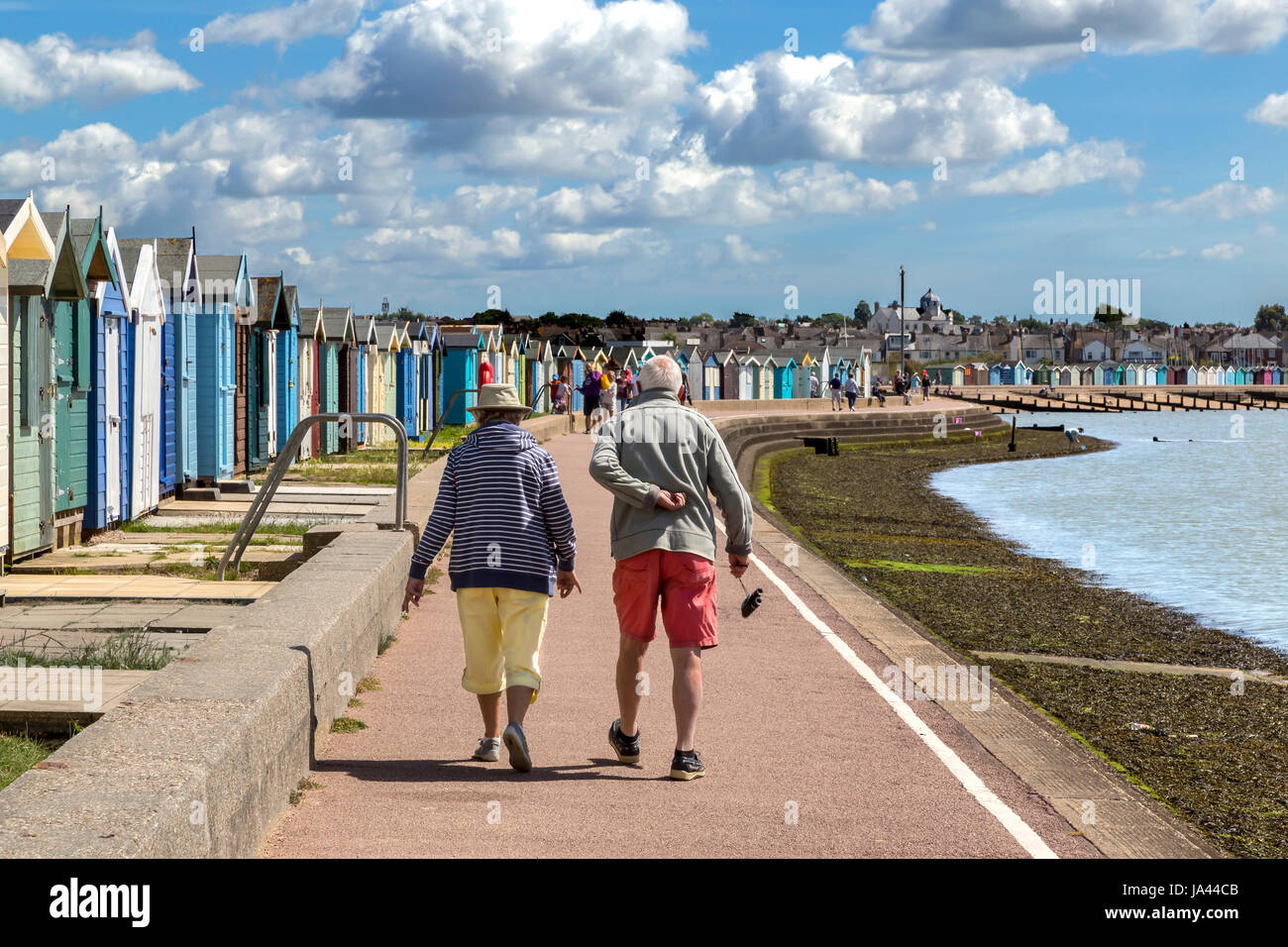 Una coppia di anziani a piedi lungo il lungomare di BRIGHTLINGSEA in Essex. L'uomo sembra soffrire di un Male all'indietro. Foto Stock