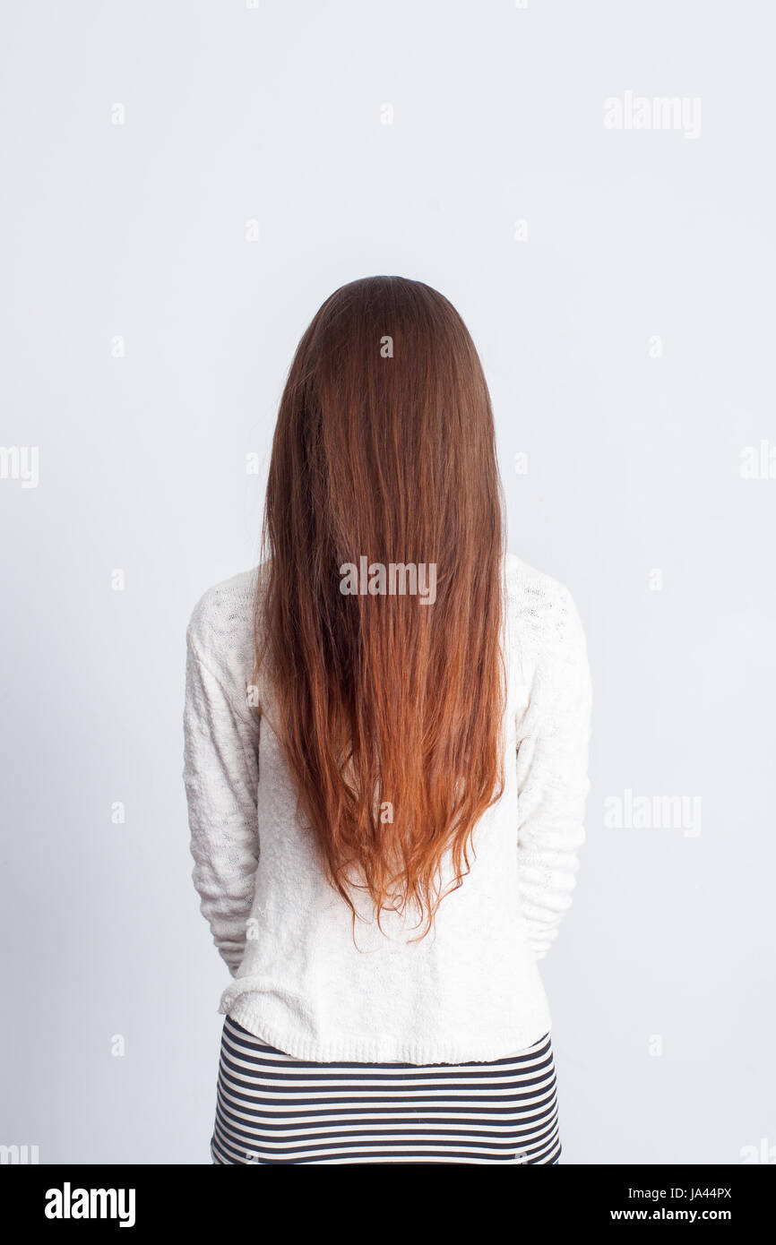 La ragazza con i capelli lunghi scary in piedi su uno sfondo grigio Foto Stock
