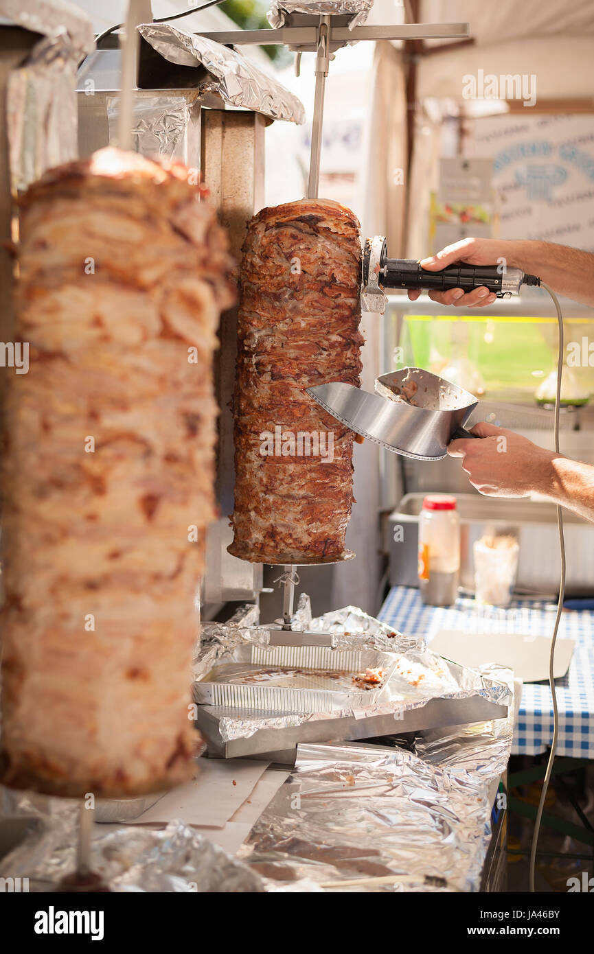 Le mani del cuoco che con coltello elettrico tagliare il döner kebab. Il Kebab è un piatto tipico della Turchia. Foto Stock