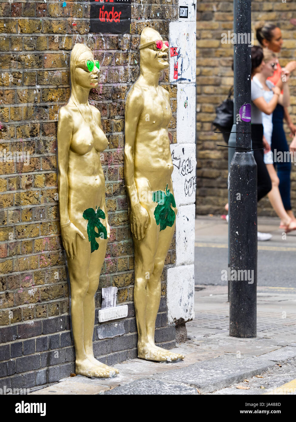 Oro dipinta maschio e femmina 3D rilievo le statue di UrbanSolid, a Londra il popolare Brick Lane nella zona est di Londra. Foto Stock