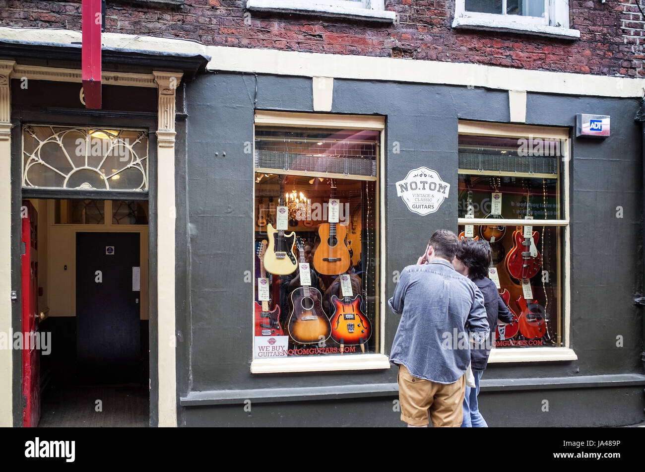 Tin Pan Alley Guitar Shop - passers by view le chitarre d'epoca in vendita nel negozio No.Tom nella storica Denmark Street nel centro di Londra Foto Stock