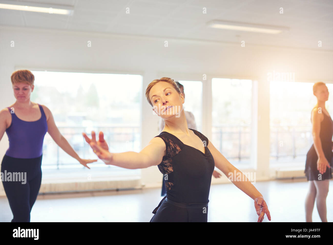Donna adulta in piedi e in posa mentre balli in classe di balletto. Foto Stock