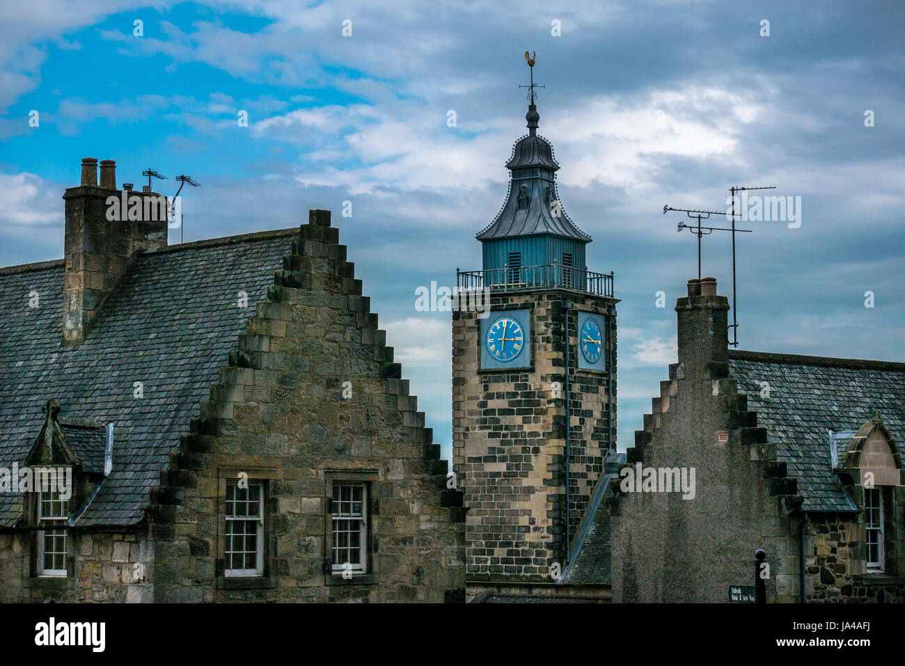Antichi edifici storici nella città vecchia, Stirling, Scozia, Regno Unito, con l'orologio della torre del Tollbooth e tetti a gradoni contro il cielo blu Foto Stock