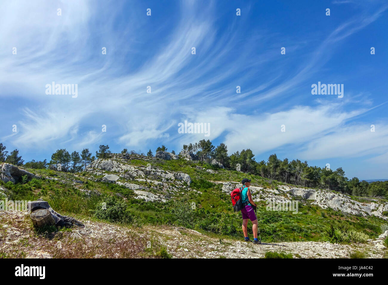 Femmina walker, escursionista in pantaloncini corti, con zaino in spalla e cielo blu con nuvole cirrus Foto Stock
