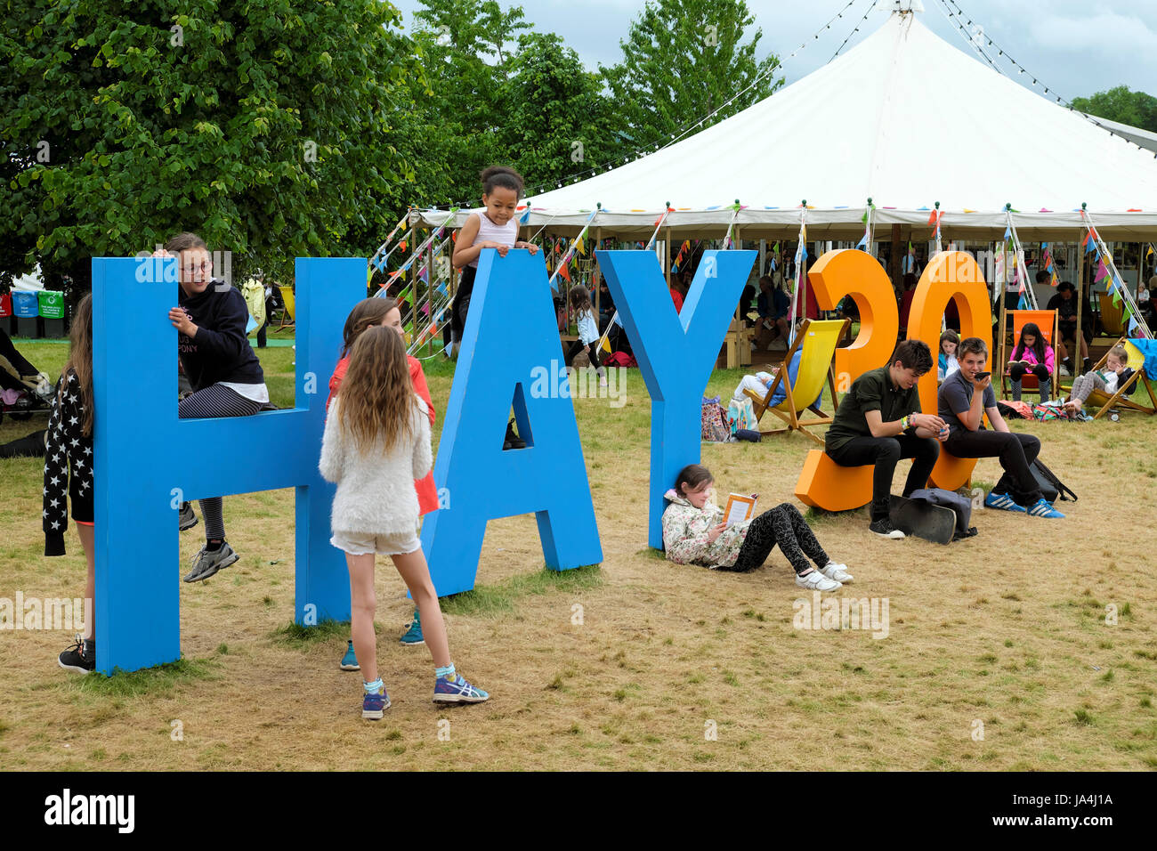 Una ragazza a leggere un libro mentre i ragazzi e le ragazze gioco arrampicata e saltando sul fieno 30 firmare al 2017 Hay Festival, Hay-on-Wye, Wales UK KATHY DEWITT Foto Stock