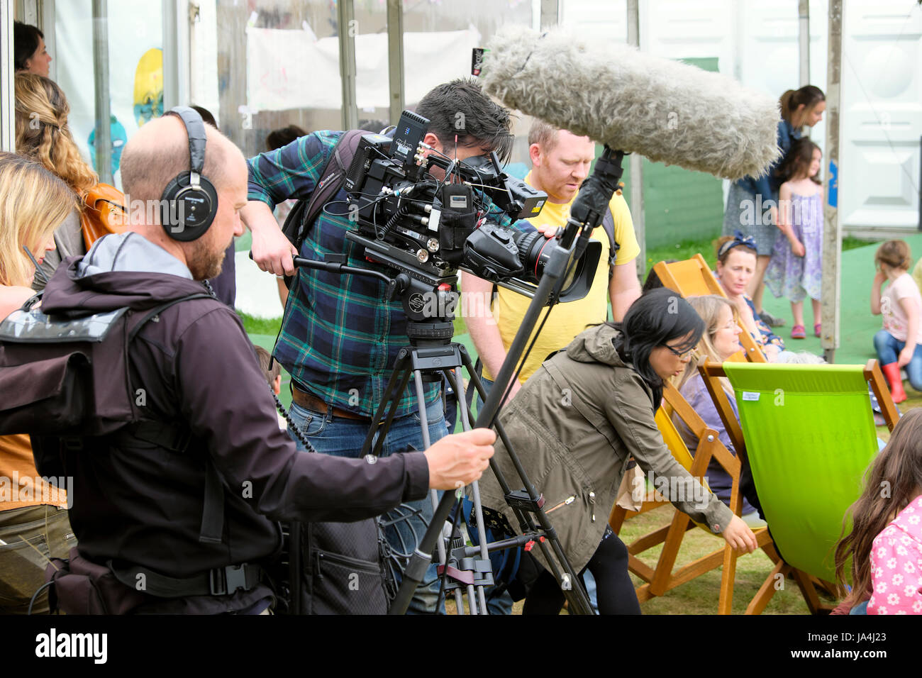 Video macchina fotografica e ingegnere del suono con boom di filmare persone sedute su sedie a sdraio al Festival Hay, Hay-on-Wye in Galles UK KATHY DEWITT Foto Stock