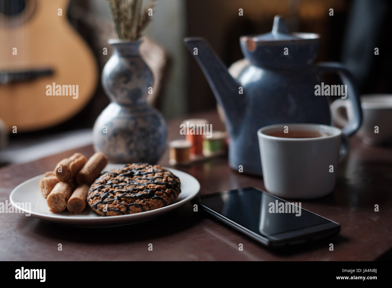 Preparazione per il tè del mattino. Una tazza e una teiera sul tavolo sono tra i graziosi dettagli interni. Foto Stock