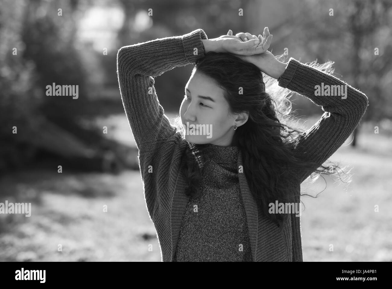 Una bella ragazza asiatica sta in abiti modesti nel mezzo di un vicolo nel parco Foto Stock