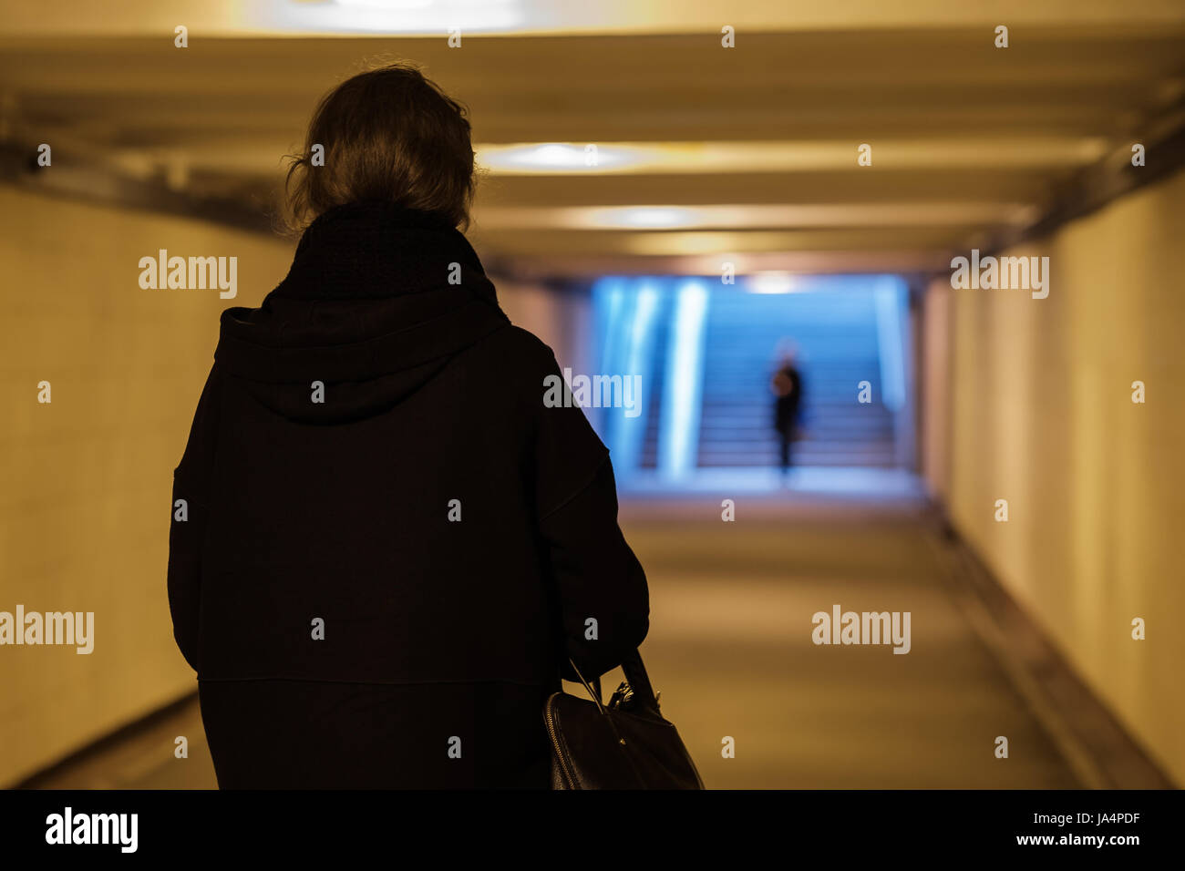 Una ragazza vestiti di nero è camminare lungo un passaggio sotterraneo. Foto Stock