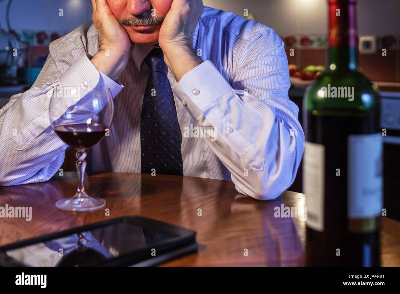 Imprenditore maschio bere vino dopo la giornata di lavoro, cercando di dimenticare i problemi Foto Stock