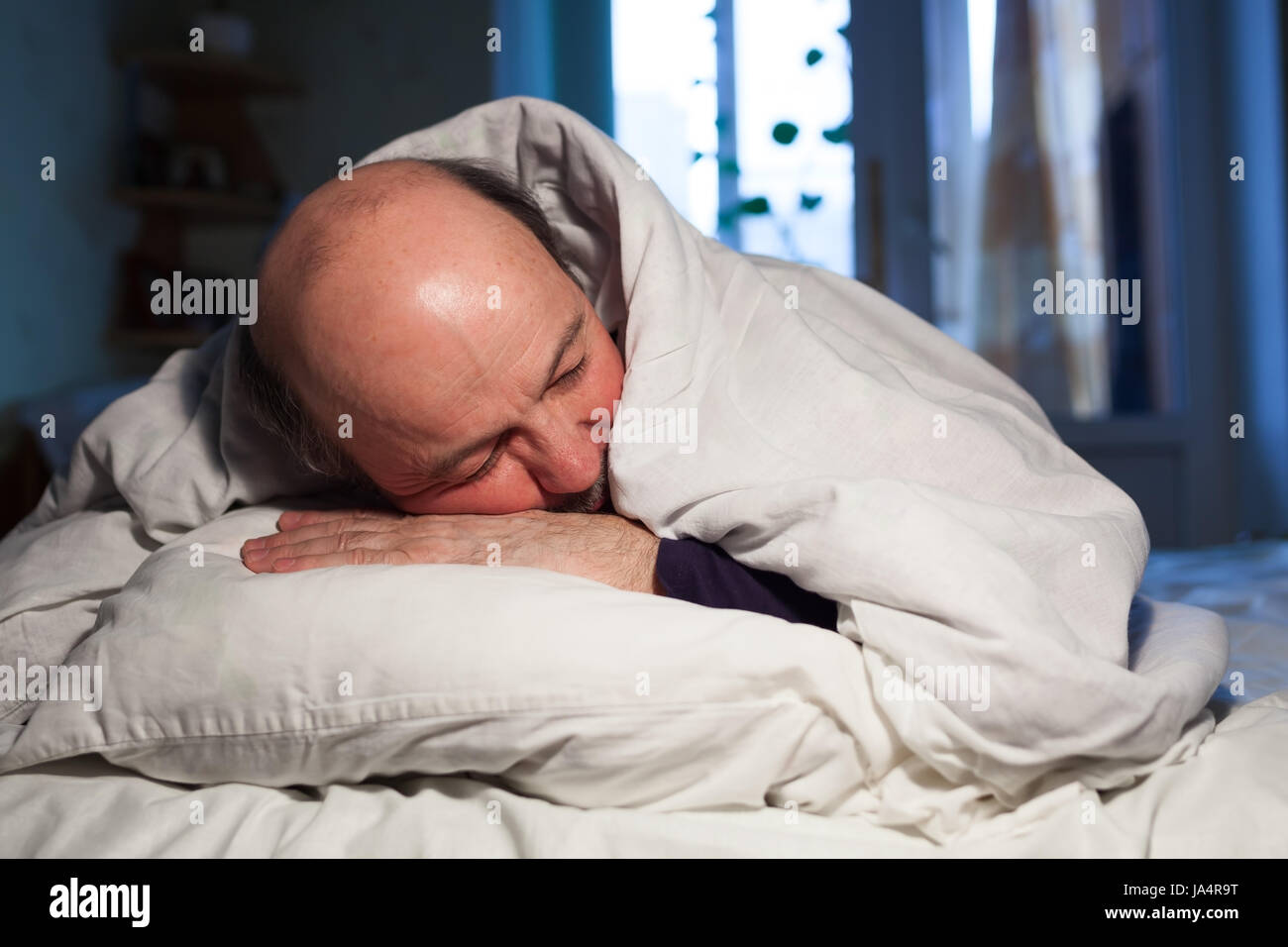 L'uomo anziano è addormentato veloce, ricoperto da una coltre bianca. Un sano sonno durante la notte Foto Stock